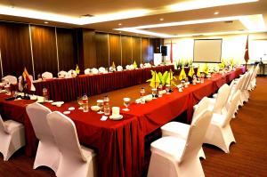 una gran sala de reuniones con mesas largas y sillas blancas. en Ameera Hotel, en Pekanbaru