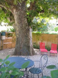 una mesa y sillas sentadas bajo un árbol en Location& gîtes, en Sarrians 2 fotos más