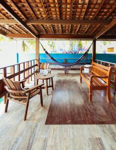 a room with two wooden chairs and a hammock at Pousada Santa Fé in Porto De Galinhas