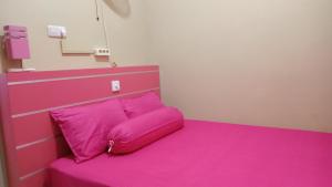 a pink bed with a pink headboard and a pink pillow at Kanalan Homestay Banyuwangi in Banyuwangi