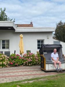 un hombre sentado en un banco frente a una casa en Ferienhaus Thönnes en Norderney