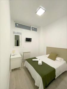 a white bedroom with a bed and a table at HOSPEDAJE LA PAZ in Madrid