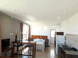 1 dormitorio con cama, mesa y cocina en Bahia dorada departamentos en Quequén