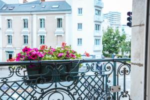 uma varanda com um vaso de flores em Hotel De La TA em Rennes