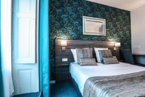 um quarto de hotel com uma cama e uma parede azul em Hotel De La TA em Rennes