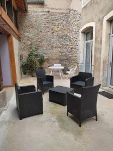 un patio con sillas, una mesa y una pared de piedra en Maison Gîte Nanie en Arbois