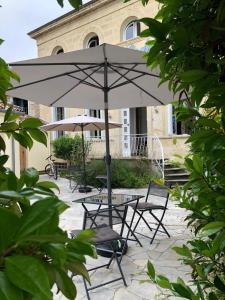 une table et des chaises avec un parasol en face d'un bâtiment dans l'établissement Le Rodin Bazas, à Bazas