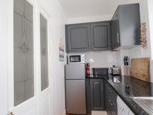 a kitchen with black cabinets and a refrigerator at 18b New Street in Buckie