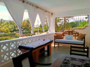 a balcony with a table and chairs and a large window at Watamu Solana Apartments in Watamu
