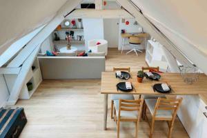 Cette chambre mansardée comprend une table et des chaises. dans l'établissement Sous Les Nuages, à Rouen