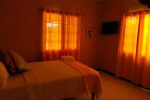 a bedroom with a bed and two windows with curtains at Unity Villa 3 bedroom with fans Wifi Parking in Montego Bay