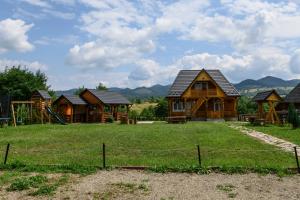 a group of wooden cabins in a field with a grass yard at Casa Cupcea in Budeşti