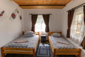 two beds in a room with two windows at Casa Cupcea in Budeşti