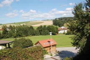 a view of a house with a green field and trees at Ferienwohnung am Wirtsgarten in Bad Birnbach