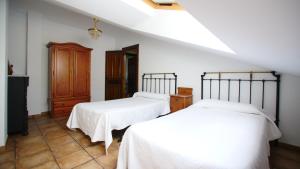 two beds in a room with white sheets at Casa Rural Plaza Vieja Saldaña in Saldaña
