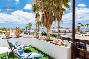 patio z krzesłami i palmami na balkonie w obiekcie Vivienda Vacacional Timanfaya w Puerto del Carmen