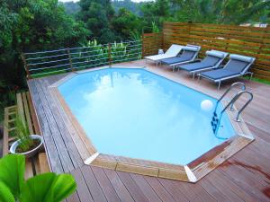 una gran piscina en una terraza de madera con sillas en Serenity en Gros-Morne