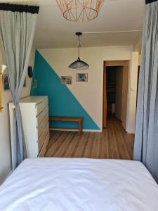 1 dormitorio con cama blanca y pared azul en La Mongie Yes !, en Bagnères-de-Bigorre