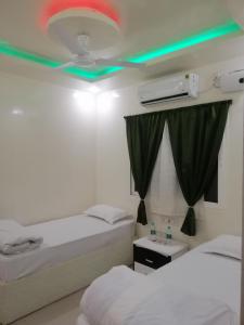 Zimmer mit 2 Betten und einer Decke mit grüner Beleuchtung in der Unterkunft RAJHAT MARANAO House in Bodh Gaya