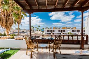 balkon z krzesłami i stołem oraz widokiem na budynek w obiekcie Vivienda Vacacional Timanfaya w Puerto del Carmen