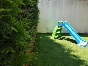 een blauwe en groene plastic glijbaan in een tuin bij Porto In Sight, 4 Kids in Vila Nova de Gaia