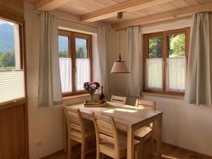 a dining room with a table and chairs and windows at Kurzenwirt - Ferienwohnungen in Kiefersfelden