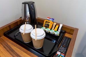 twee kopjes koffie bovenop een koffiezetapparaat bij Royal Park Hotel in Londen