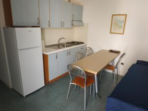 eine kleine Küche mit einem Tisch und einem weißen Kühlschrank in der Unterkunft La Maison Du Parc in SantʼAndrea Apostolo dello Ionio