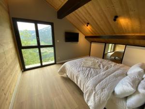 a bedroom with a bed and a large window at CHALET CONFIDENTIEL VALMOREL - Chalet de Haut de Gamme 4 étoiles 12 personnes in Doucy