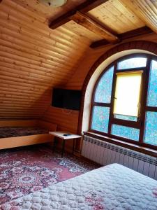 a room with a bed and a tv and windows at Під горою in Volovets
