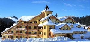 un gran edificio amarillo cubierto de nieve en Apartmán u Vlka en Donovaly