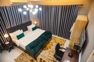 a bedroom with a bed and a desk and a television at The Avery Suites, East Legon in Accra