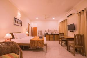 a bedroom with a bed and a desk and a television at Primavera Holiday Homes-GOA-CANDOLIM BEACH WITHIN 300 MTRS-GOAN FAMILY HOSPITALITY in Candolim