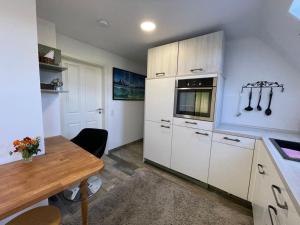 uma cozinha com armários brancos e uma mesa de madeira em Grüner Baum em Langenbrand