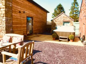 un patio trasero con bañera de hidromasaje y 2 sillas en Anvil Cottage en Mold