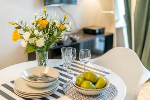 a table with a bowl of fruit and a vase of flowers at Poznanska Serviced Apartments in Warsaw