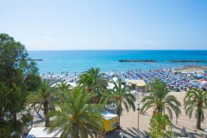 a beach with palm trees and umbrellas and the ocean at H11 SEA UNDER THE HOUSE - Arma di Taggia - Liguria in Taggia