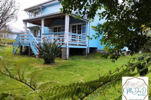 ein blaues Haus mit einer großen Veranda auf einem Hof in der Unterkunft La Villa Des O, sentier Grand Bassin in La Plaine des Cafres