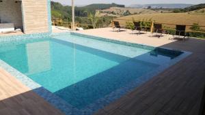 a swimming pool with chairs and a view of a hill at Pousada Ipê da Serra in Socorro