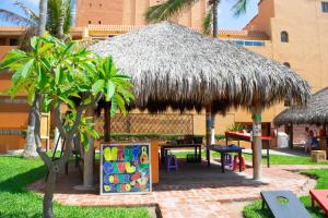 a hut with a picnic table and a table with a sign at Costa de Oro Beach Hotel in Mazatlán