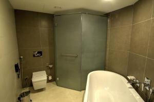 a bathroom with a shower and a tub and a toilet at Ramee Dream Resort in Seeb