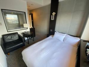 ein Schlafzimmer mit einem großen weißen Bett und einem Stuhl in der Unterkunft ＦＵＲＡＮＯ ＮＡＴＵＬＵＸ ＨＯＴＥＬ - Vacation STAY 68188v in Furano