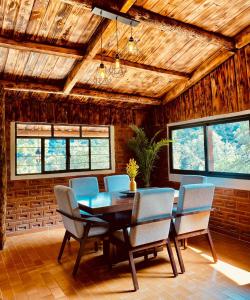 - une salle à manger avec une table, des chaises et des fenêtres dans l'établissement Quinta del Río, à Villa del Carbón