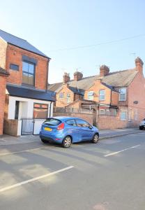 a blue car parked on the side of a street at The Quirky Cottage in Leicester