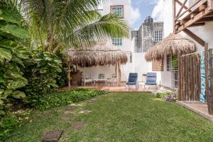 un patio trasero con un patio con sillas y un edificio en Casa Nona Rosa, en Cancún