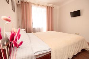 - une chambre dotée d'un lit avec des draps blancs et des fleurs roses dans l'établissement APARTMENT on Sobornyi Avenue 61, à Oleksandriya