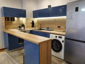 a kitchen with blue cabinets and a washing machine at Monteverde Ski Lift Apartment Bansko in Bansko