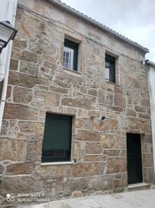 un antiguo edificio de piedra con 3 ventanas en Casa en el centro histórico de Corcubión., en Corcubión