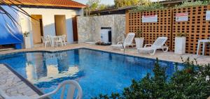 a swimming pool with white chairs and a table and a building at Hotel Urubupunga in Ilha Solteira