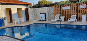 a swimming pool with white chairs and a fireplace at Hotel Urubupunga in Ilha Solteira